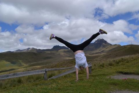 student doing a cartwheel in front of green rolling hills