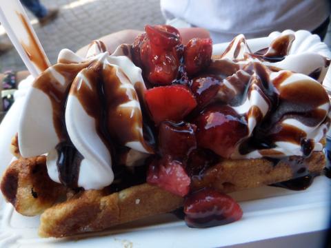 a waffle covered in chocolate sauce, whipped cream, and strawberries