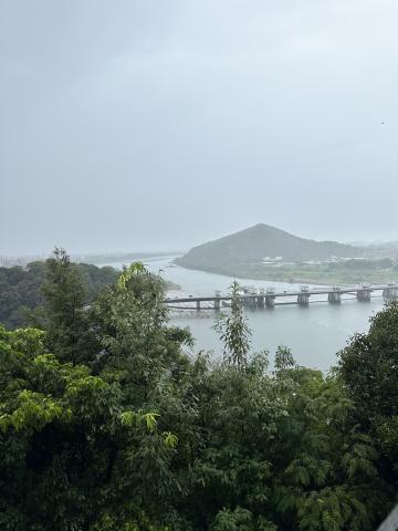 A view from Inuyama castle on a rainy day with a mountain in the back overlooking a river. 