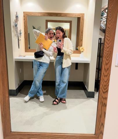 A fun mirror picture of two girls, one holding a bright orange envelope containing study abroad paperwork. 