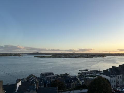 A sunset over the ocean, viewed from a hill with houses in the foreground