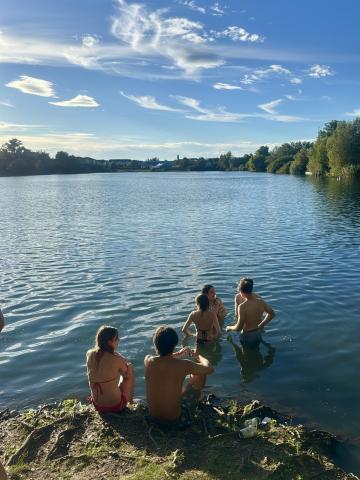 People sitting on the ground by a lake