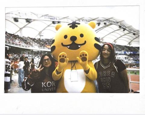 This is a photo of my friend and I are standing next to the KU tiger mascot.