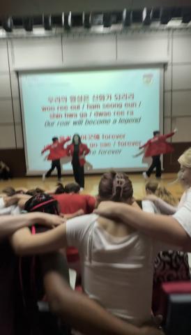 In this image, students are seen with their arms around their neighbor, bending down to the rhythm of the song. 