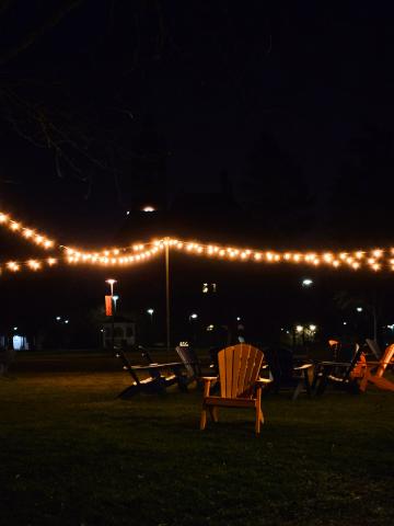 A warm scene of campus lights and lawn chairs at night.