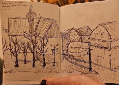 A pen sketch in a small notebook of a winter's view in Budapest, showing a side street, tall houses, and leafless trees.