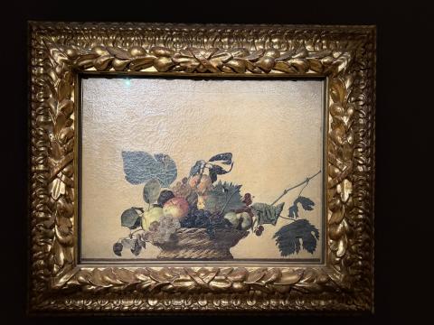 A painting with a pale yellow background and a bowl of grapes and pears.  