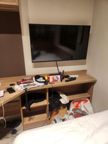 A television positioned near the foot of the bed inside a studio apartment.
