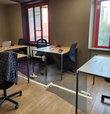 A shared office workspace with desks, office chairs, and large windows inside a consulting company in Milan.