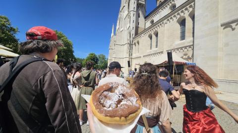 A shot showcasing the Mittelalterfest at Klosterneuberg, with fried dough and attendees in period attire dancing to live music.