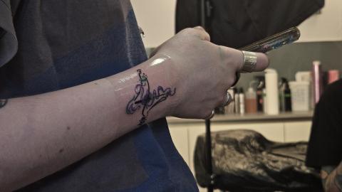 My roommate's fresh tattoo - black, green, and purple; flowy designs around a traditional 4/4 conducting pattern.