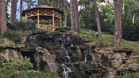 A gazebo atop tiny waterfalls flowing against smooth rocks in Türkenschanzpark.