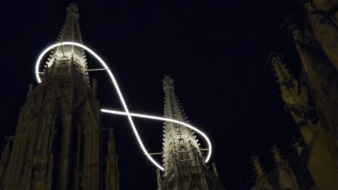A view of Vienna's Votivkirche from below, showcasing the infinity-sign light instillation that shines at night.