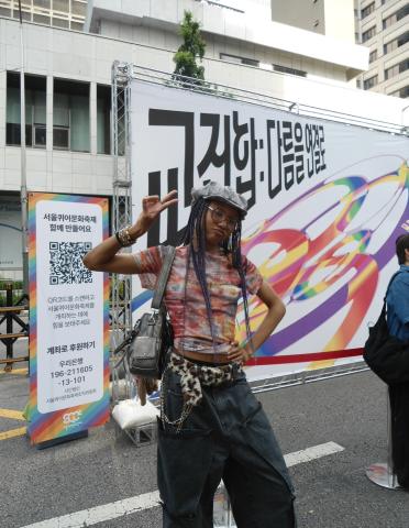 A picture of me wearing a very colorful outfit at pride while holding up a peace sign.
