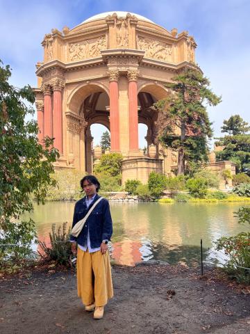 Person stands by waterfront surrounding a dome-shaped Roman-inspired monument.