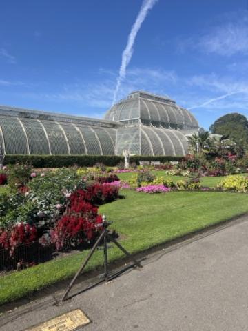 An image of a greenhouse located at Kew Gardens with clear skies in the background