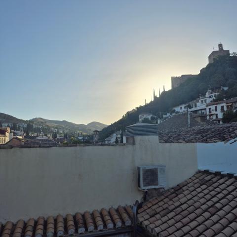 The Alhambra sits atop a hill with the sun rising in the background.