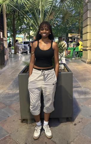 Student wearing cargo capri pants with a black tank top with a lace trip, a gold arm cuff, and white sneakers