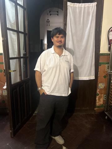 student wearing sneakers, brown cargo pants, and a white polo.