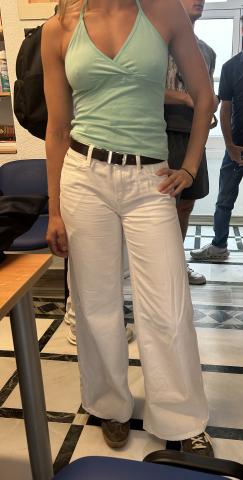 Student wearing teal tank top, white jeans with a black belt, and sneakers