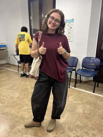Student wearing black barrel jeans, tan clogs, and an asymmetrical cut shirt