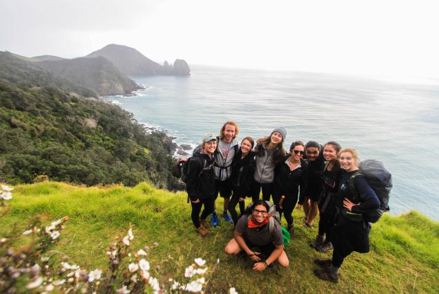 a group of students pose for a photo while backpacking on New Zealand's coast