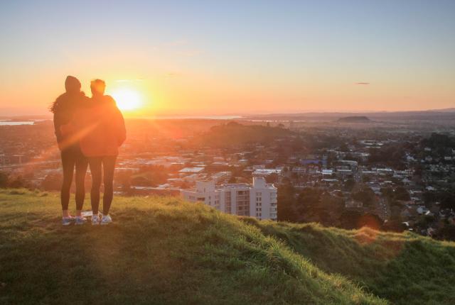 two students watch the sunset atop Mount Eden in Auckland
