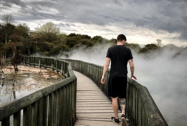 a student walks on a smoky bridge in Rotorua's Kuirau geothermal park in New Zealand