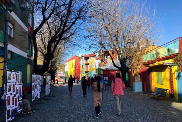 a group of students walk between the colorful buildings of La Boca, Buenos Aires