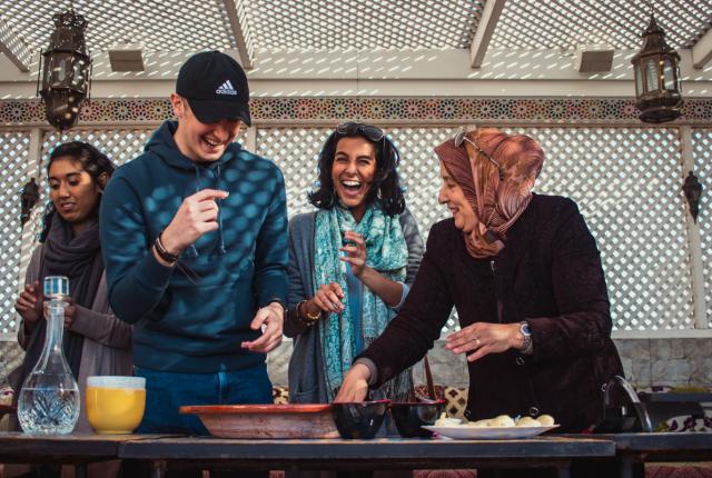students laugh while cooking with their host mom in Rabat