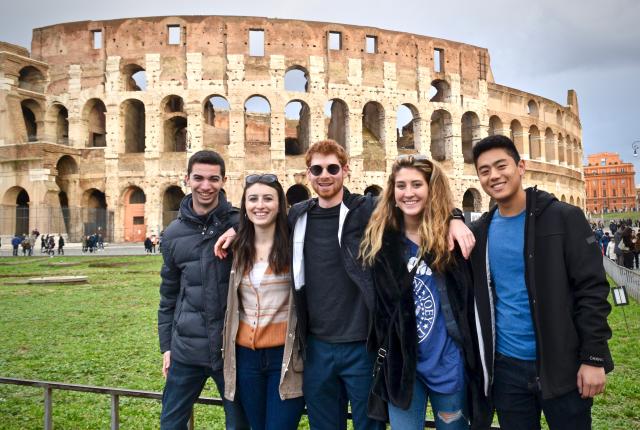 a group of students posing for a photo in front of the Colosseum
