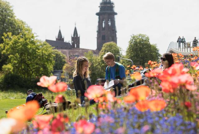 students sit in the flowers by Cathedral Square in Freiburg