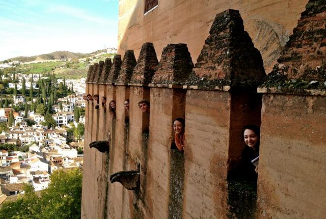 students peaking their heads out of Alhambra's windows, overlooking the city of Granada