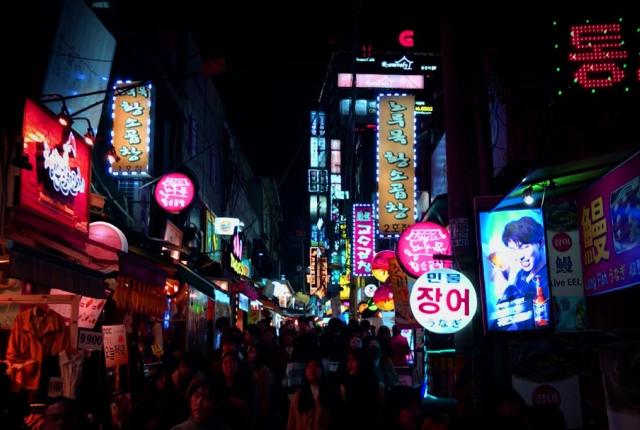 the crowded streets and neon signs of Hondae, Seoul at night