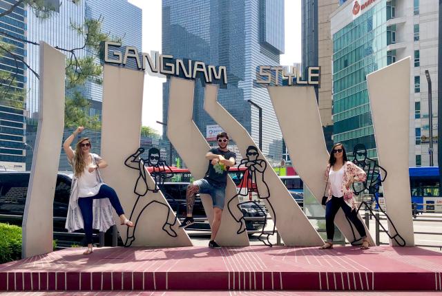 three students pose for a photo in front of the Gangnam Style mural in Gangnam, Seoul