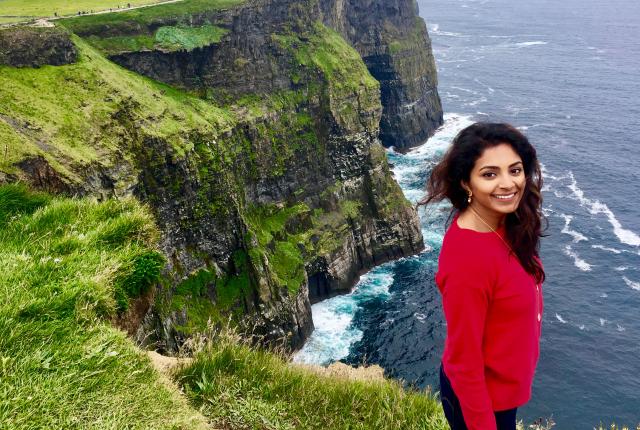 a student sits cliffside at the Cliffs of Moher