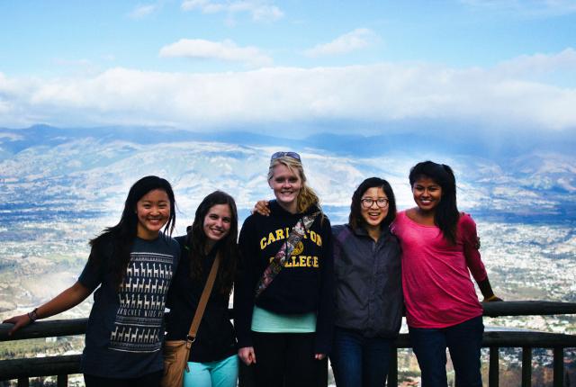 a group of students pose for a photo from atop the mountains in Quito with a backdrop of the city