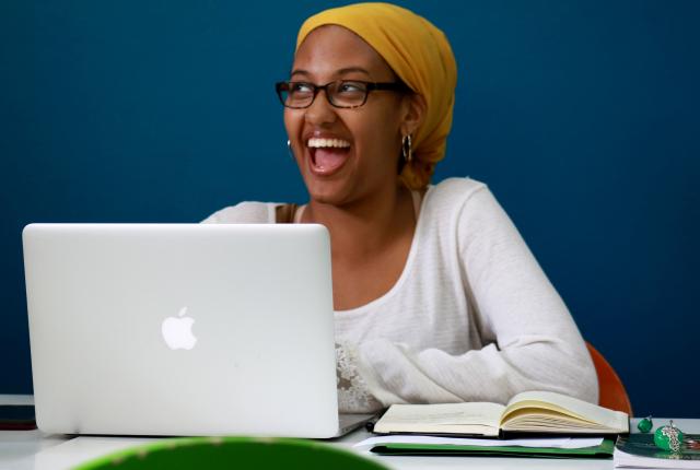 a student smiling while using their laptop