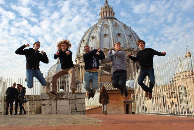 students jump to pose for a fun photo in front of St. Peter's Basilica