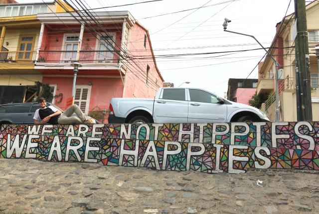 a student posing for a photo with the "we are not hippies, we are happies" mural in Valparaíso, Chile