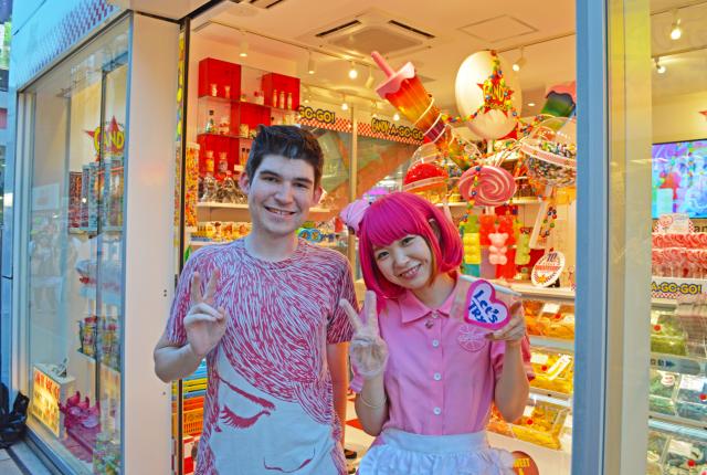 a student poses for a photo with a staff member at a candy store in Harajuku