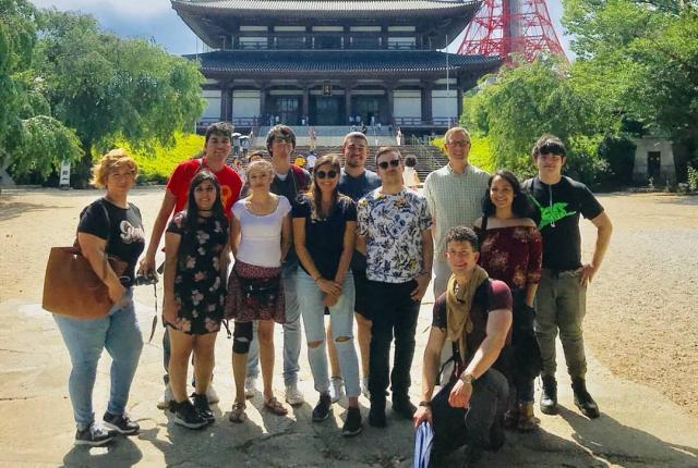 students posing for a photo in front of Tokyo Tower and a Japanese palace