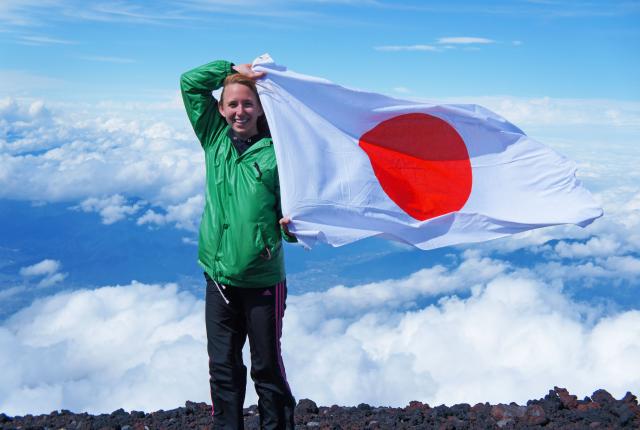 a student flies the Japanese flag at the top of Mount Fuji