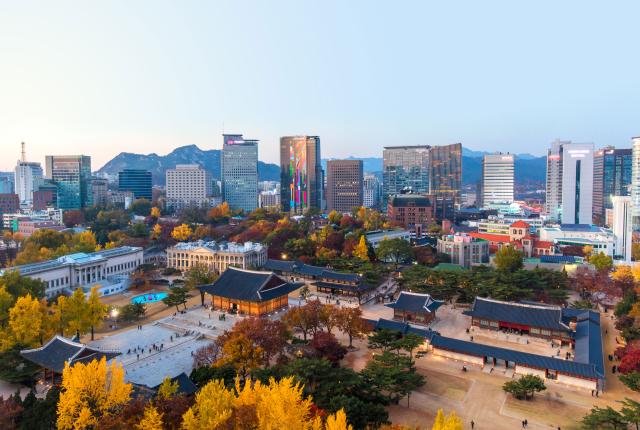 an aerial view of Deoksugung Palace and the surrounding city during fall in Seoul