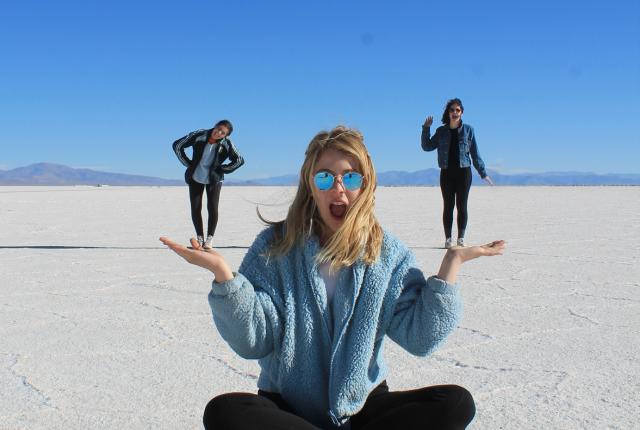 three students pose for a forced-perspective photo at Salinas Grandes salt flats