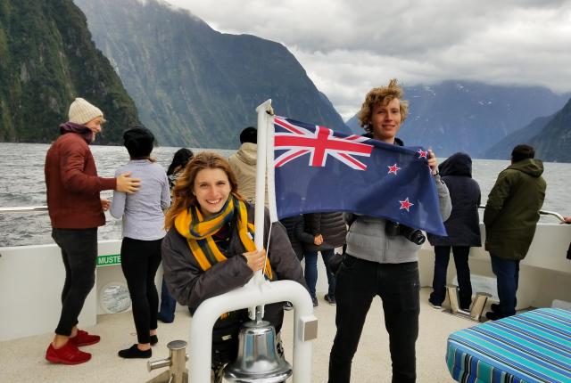 students on a boat in Milford Sound holding a New Zealand flag