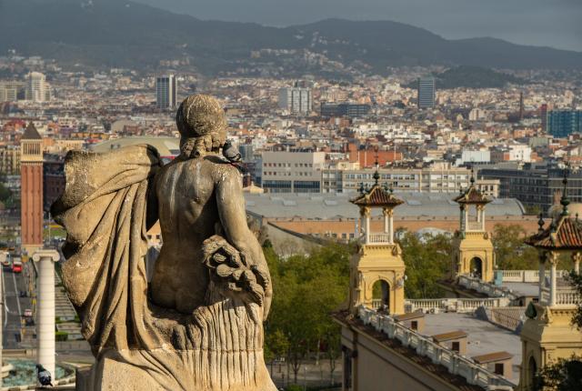 a cityscape of beautiful Barcelona behind a statue