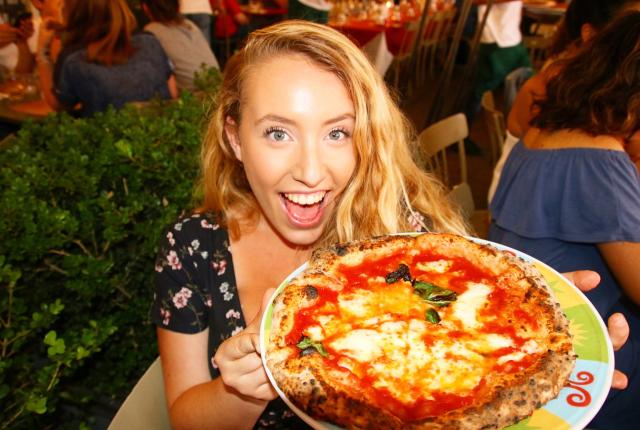 a student posing for a photo with her pizza in Italy