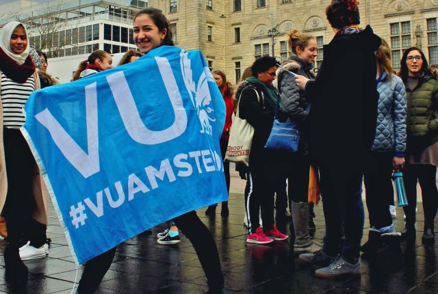 a student walking with a VU flag on a rainy day