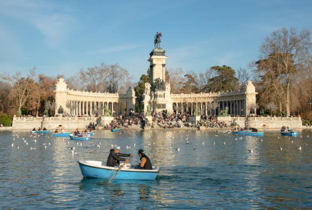 people paddling in blue boats in in Retiro Park Lake in Madrid